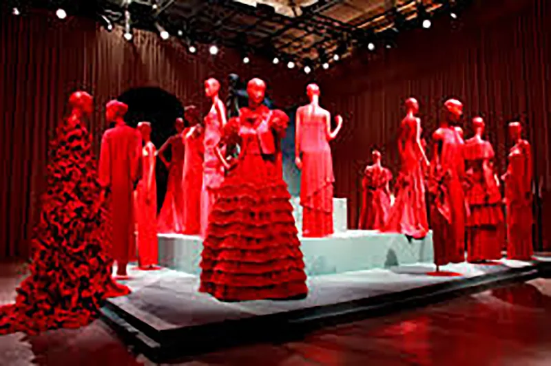 Monumental red face sculpture positioned amongst matching mannequin displays at the Forever Valentino exhibition.