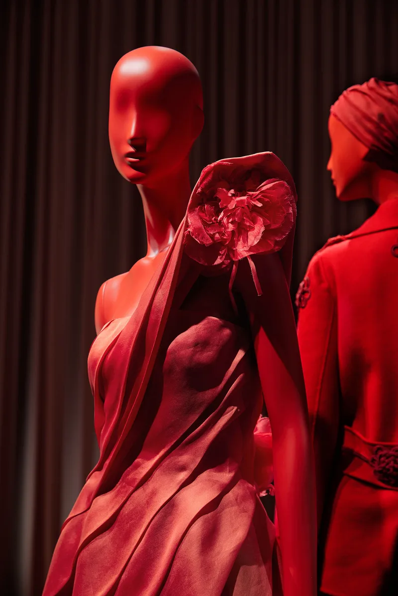 Sculptural face installation surrounded by red mannequins and coordinated fashion displays in Doha.