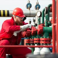 Oil and gas field technician inspecting valve during operations 