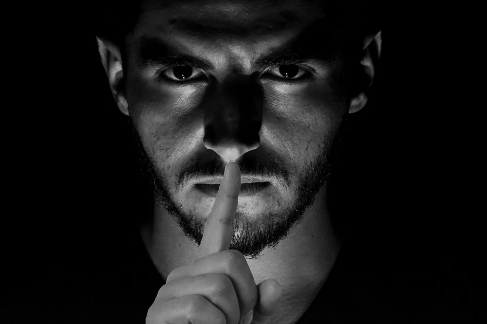 image of a man with a finger to his lips in moody black and white_careless whisper saxophonist_london saxophonist