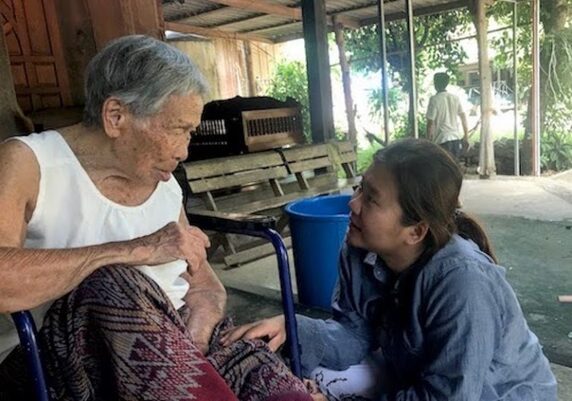 A moment of companionship between Access to Care home visit with disabled woman in wheelchair who lives alone and in poverty.