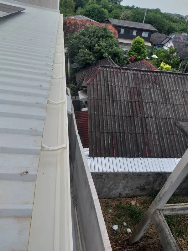 ช่างติดตั้งรางน้ำฝนหลังคาบ้าน แบบใช้วัสดุรางน้ำฝนแนวยาวที่เป็น ไวนิล VG สีขาว เป็นงานรางน้ำในไวนิล VG สีขาว ที่ทำให้กลมกลืนหลังคาดูบ้านสวยงา