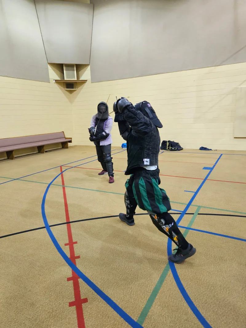 Instructor Chris and an adult student engaged in a longsword fight.