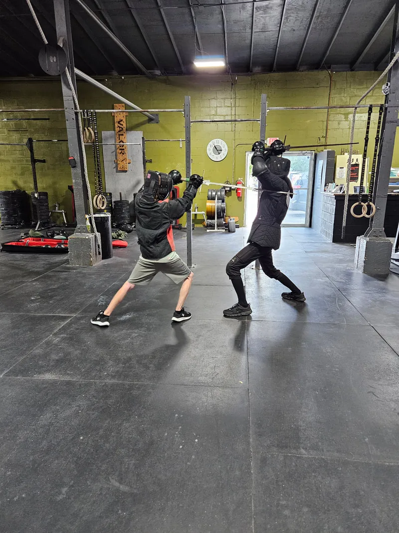 Teen student strikes Instructor Braam during a longsword fight.