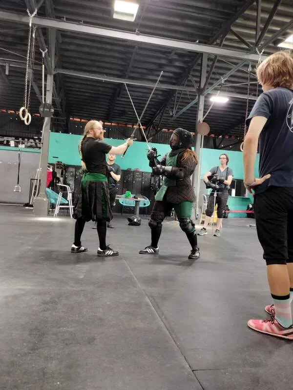 Instructors Jason and Amanda with crossed longswords during lesson.