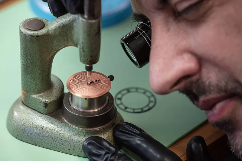 Artisan réalisant un travail de précision sur une pièce d'horlogerie