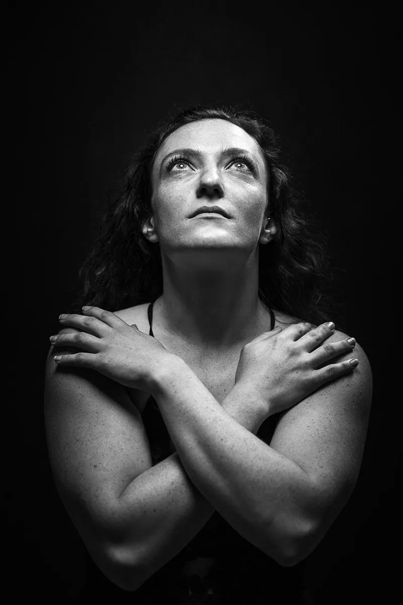 Portrait mystique d'une femme les yeux levés vers le ciel dans une posture de prière angélique