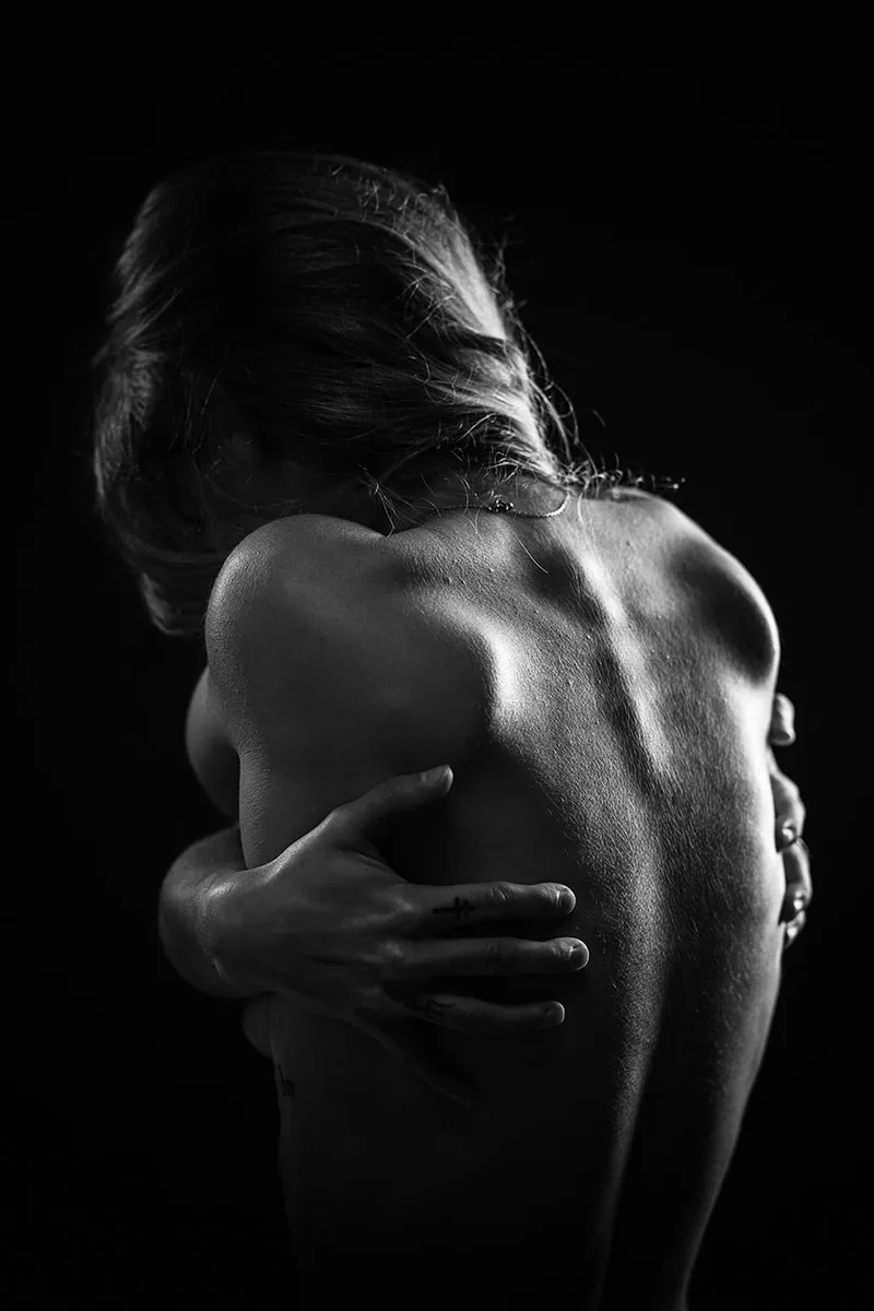 Photographie conceptuelle illustrant la solitude d'une silhouette enlacée dans l'ombre