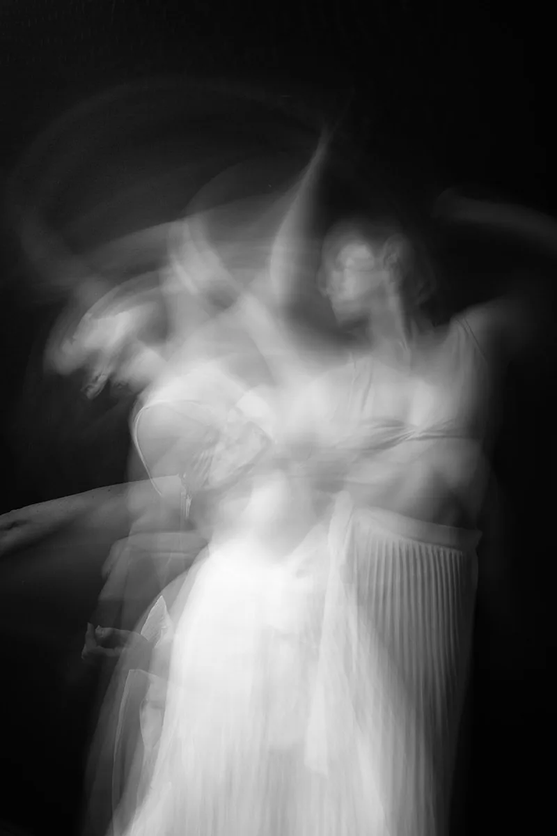 Photographie en pose longue d'une danseuse en mouvement, mêlant poésie visuelle et folie