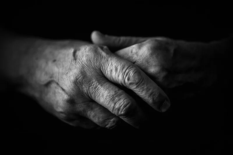 Gros plan intemporel en noir et blanc sur des mains ridées symbolisant la force d'une mère