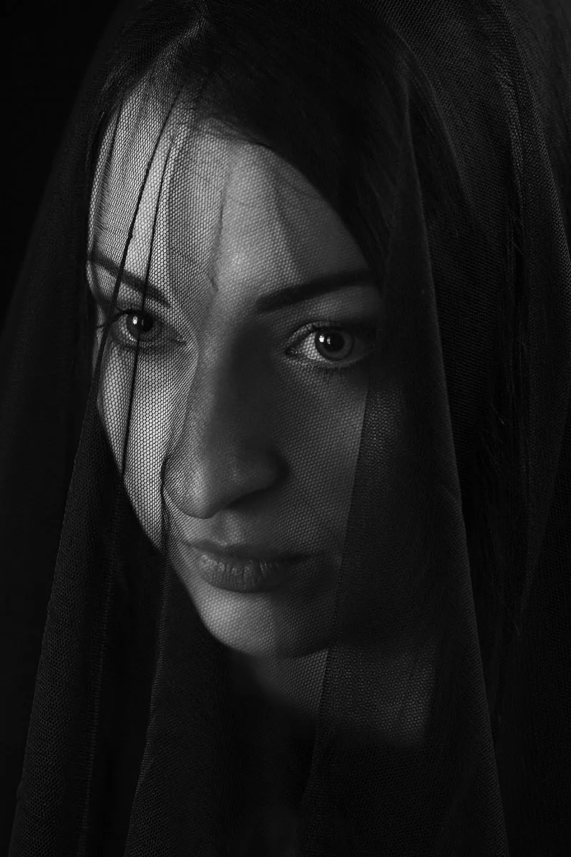 Portrait texturé en low-key d'une femme au regard mystérieux dissimulée derrière un voile