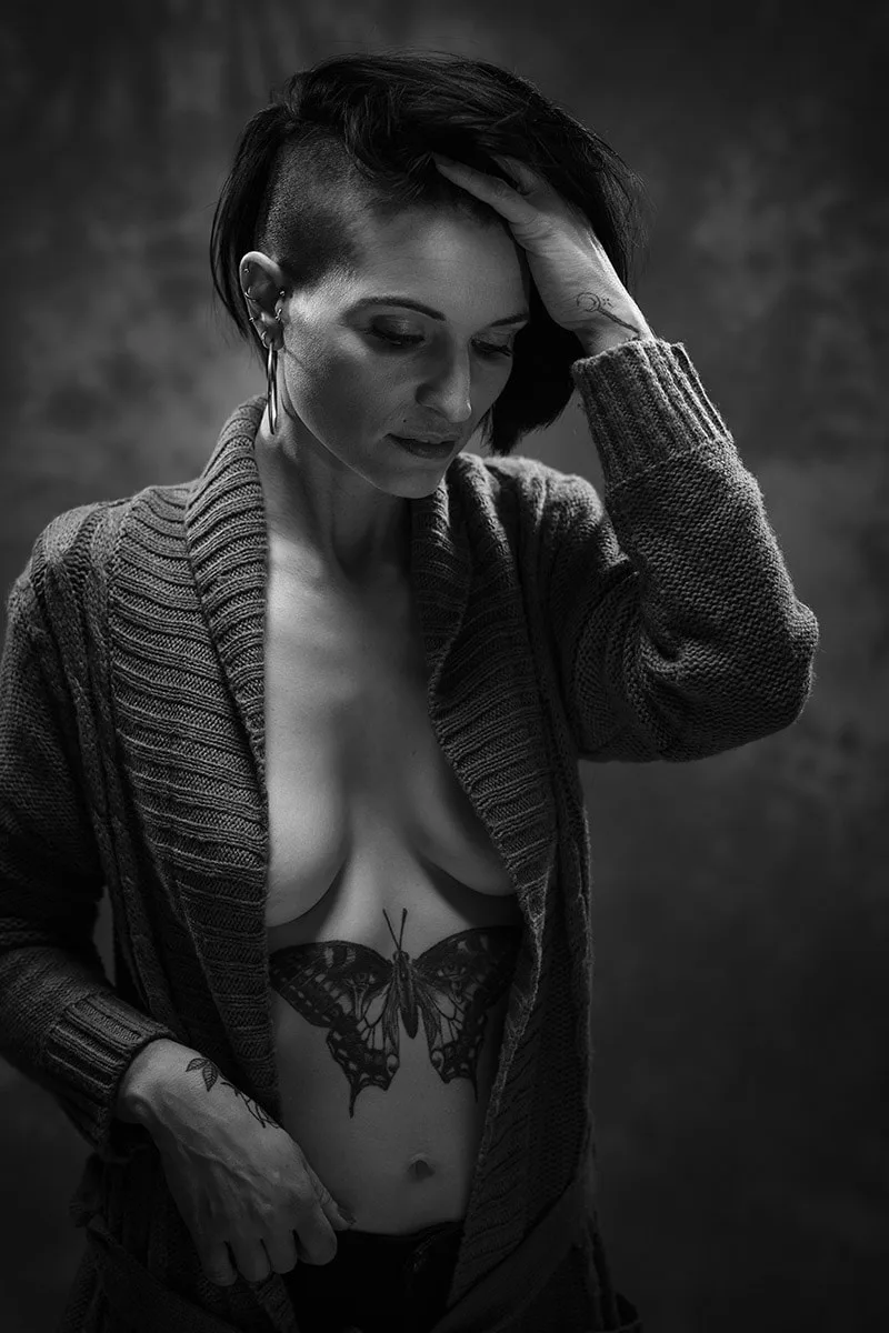 Portrait d'art féminin mêlant sensualité et douceur, mettant en valeur le tatouage et les formes du modèle