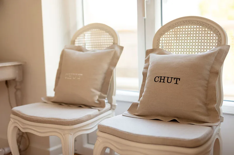 chaises couleur crème avec des coussins portant une mention 