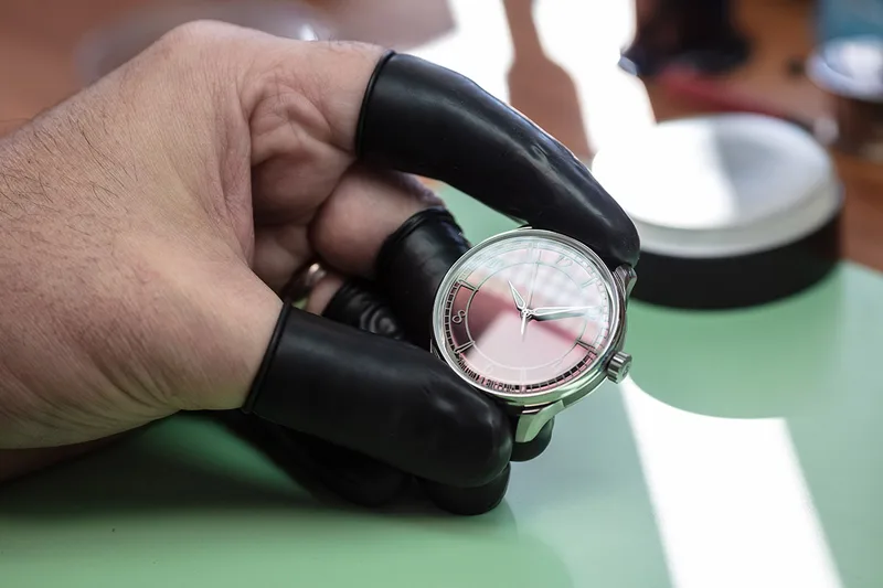 Montre en cours de fabrication tenue entre les mains d’un horloger