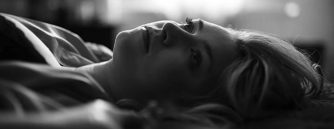 Portrait intimiste en noir et blanc d'une femme au regard chargé d'émotion en lumière naturelle