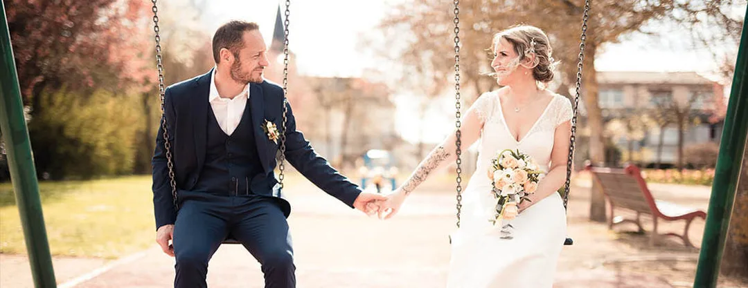 Reportage photo de mariage mettant en valeur la complicité d'un couple sur une balançoire, à travers un premier plan de fleurs