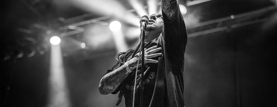 Photographie de concert en noir et blanc de Sonny Sandoval, chanteur du groupe P.O.D, en pleine performance scénique