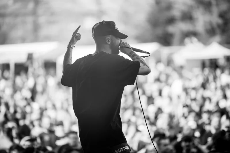 Le chanteur de Guilt Trip penché vers la foule au premier plan d'un concert en noir et blanc
