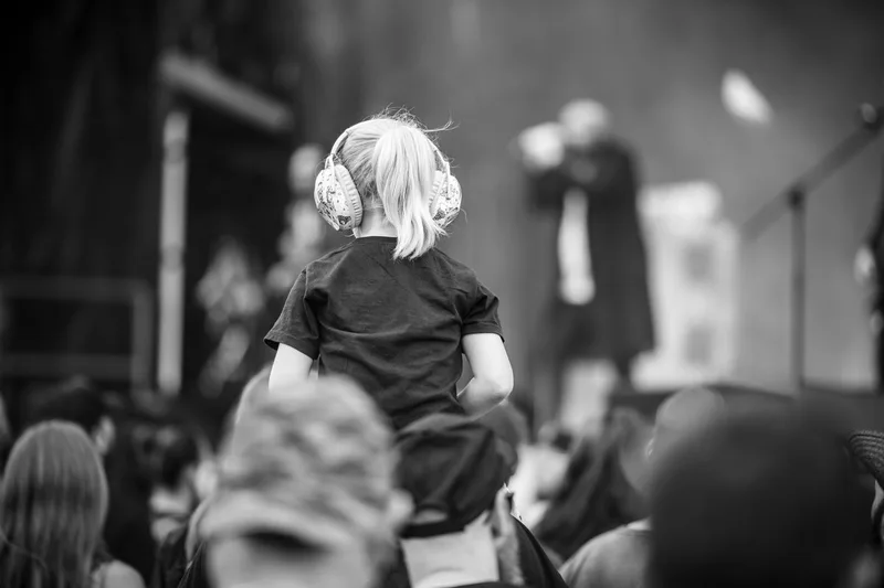 Scène touchante d'une petite fille avec un casque antibruit sur les épaules de son père face au chanteur de Psykup