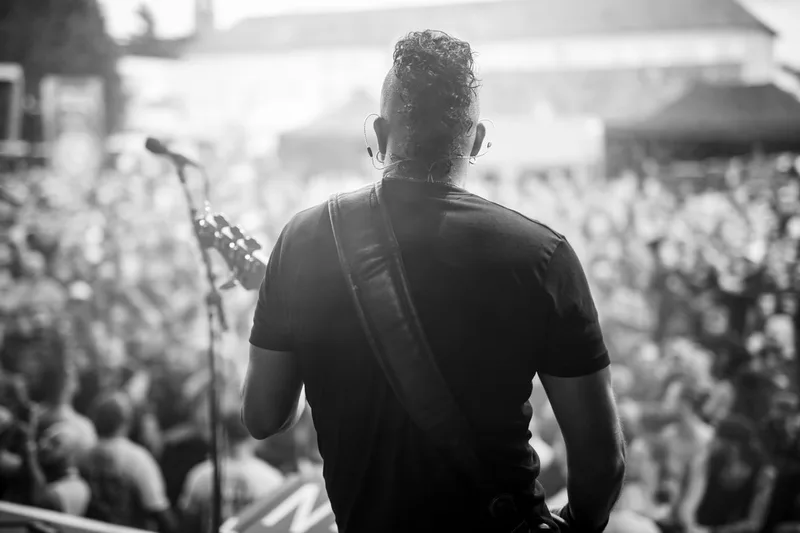 Le bassiste de Fear Factory photographié de dos, face à une immense scène et une foule compacte