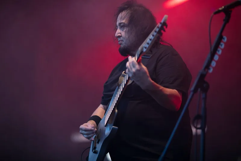 Dino Cazares, guitariste de Fear Factory, sur scène sous des éclairages écarlates
