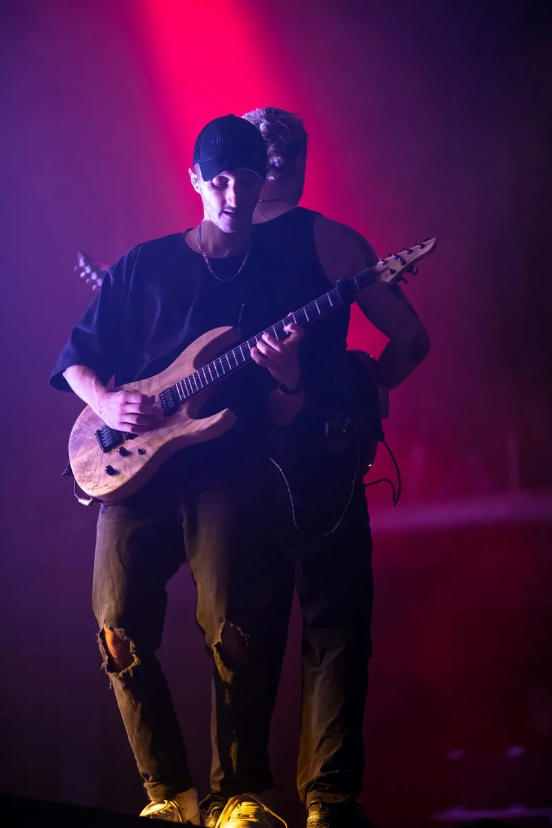Duo de guitaristes du groupe Novelists jouant ensemble dans une lumière rouge intense