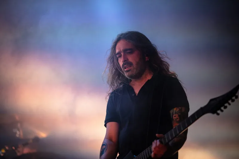 Le guitariste de Carpenter Brut performant en plein air sous un ciel de fin de journée