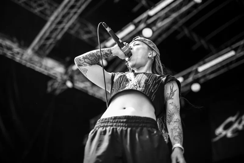 La chanteuse du projet Calcine délivrant un cri puissant sur scène en noir et blanc