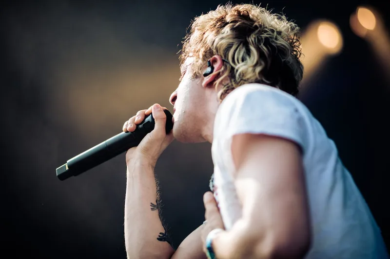 lem Richard, chanteur d'Ashen illuminé par une chaude lumière dorée sur la scène d'un festival