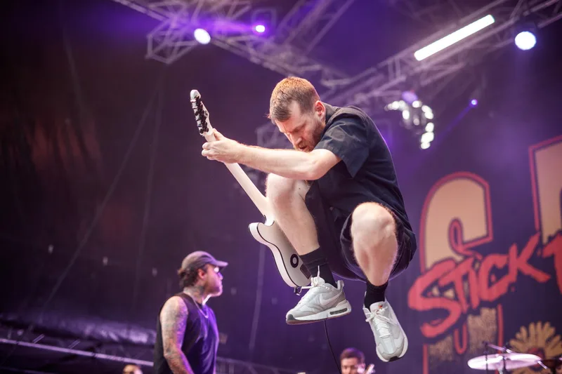 Saut spectaculaire du guitariste de Stick To Your Guns, capture d'un instant décisif sur scène