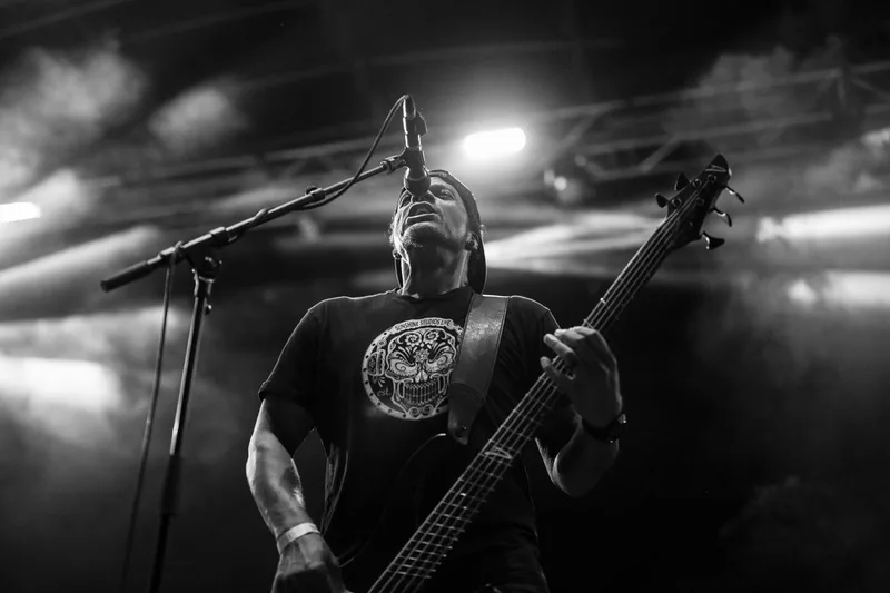 Le bassiste du groupe P.O.D accompagnant le chant au micro lors d'une session live
