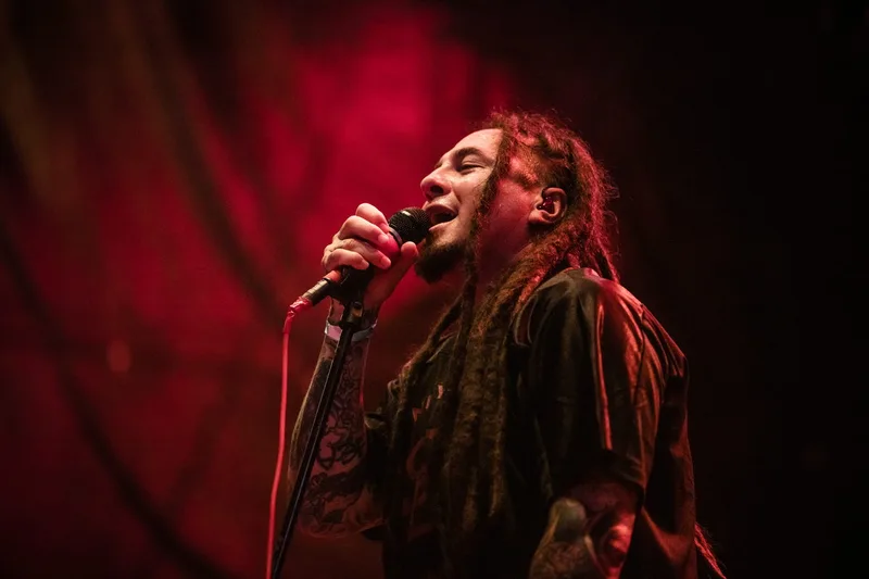 Sonny Sandoval du groupe P.O.D chantant avec ferveur sous des lumières de scène rouges