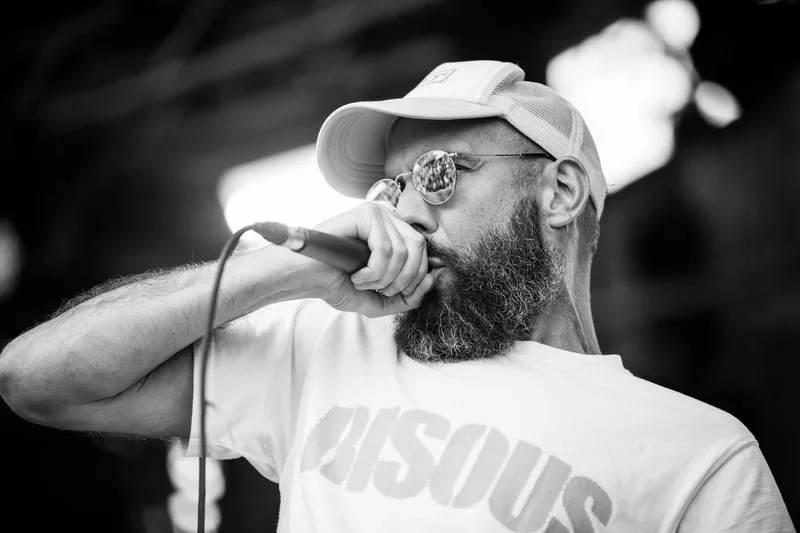 Le chanteur de Gruiiiik chantant face à la foule, le public se reflétant dans ses lunettes