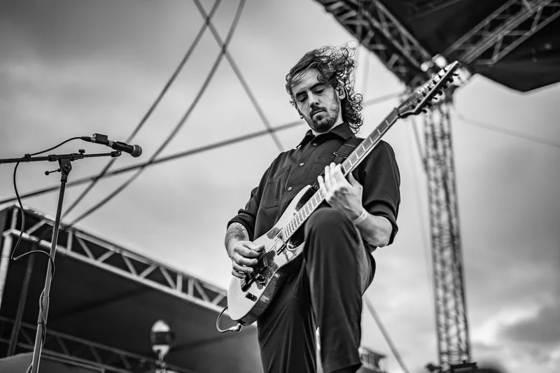 Mouvement de cheveux en noir et blanc du guitariste de Revnoir jouant en plein air