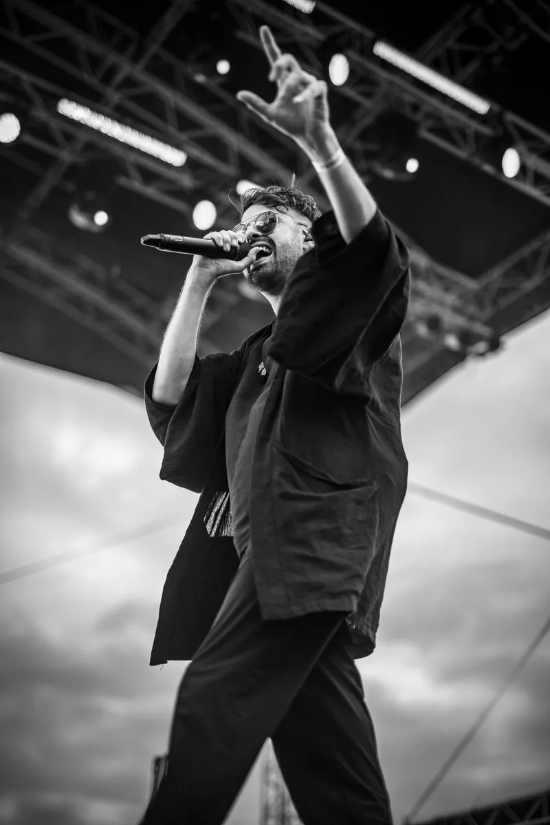 Max Rodriguez-Medallo, chanteur de Revnoir partageant un sourire avec son public sous un ciel ouvert