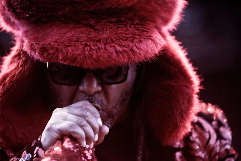Portrait de scène dynamique aux tons rouges de Benji Webbe, chanteur du groupe Skindred