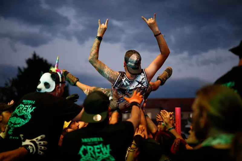 Un festivalier en plein crowd surfing porté par le public pendant le concert de Skindred