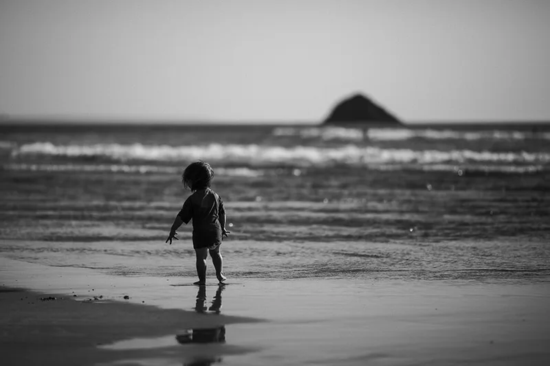 Image intemporelle d'un enfant seul face à l'immensité de l'océan en Bretagne