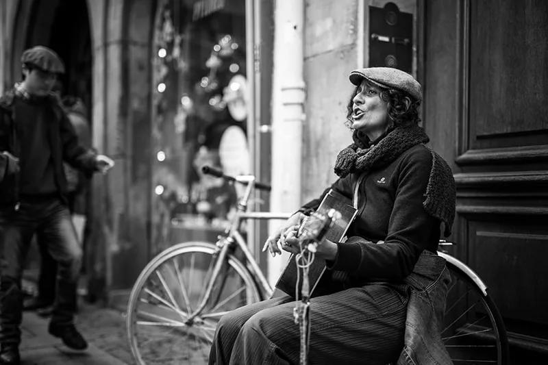 Portrait de rue à Strasbourg d'une chanteuse s'accompagnant à la guitare acoustique