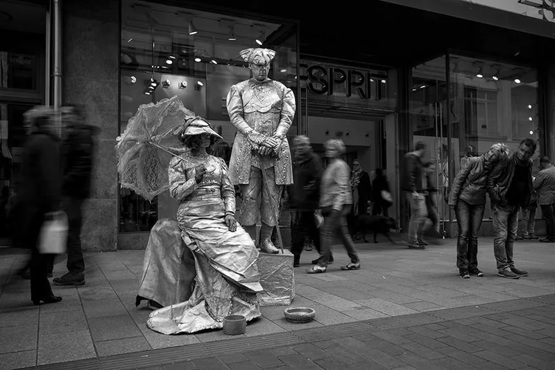 Artistes de rue costumés en automates figés dans une pose artistique en noir et blanc