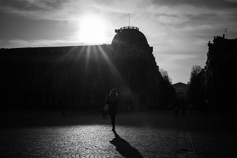 Silhouette en contre-jour transpercée par les rayons du soleil dans une rue à Lille