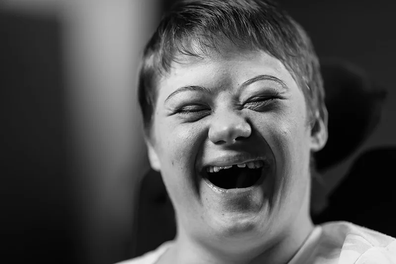 Cliché pris sur le vif d'un éclat de rire sincère et communicatif d'une personne en situation de handicap