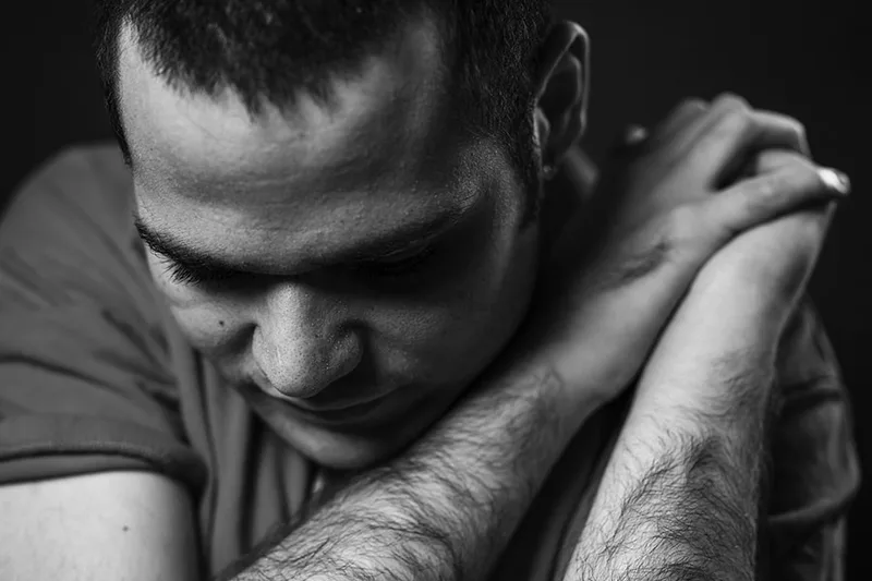 Portrait humaniste en noir et blanc d'un résident de MAS exprimant une force tranquille dans une attitude de repli