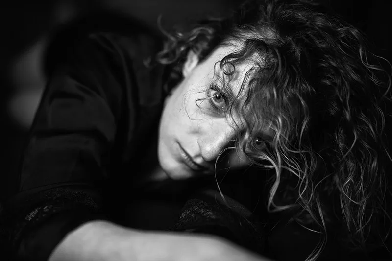 Portrait dramatique en clair-obscur axé sur l'émotion et la force du regard à travers les cheveux
