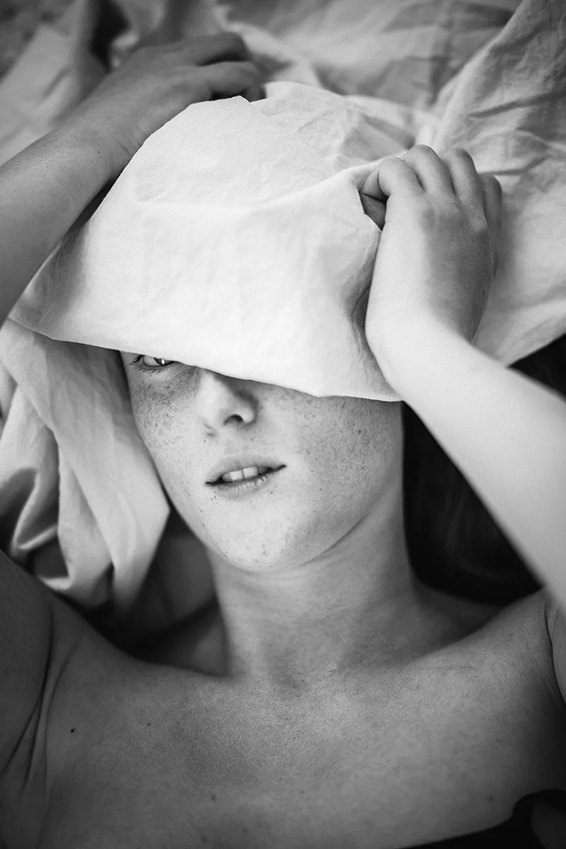 Gros plan pudique sur l'œil et le regard d'une femme en partie dissimulée derrière un drap