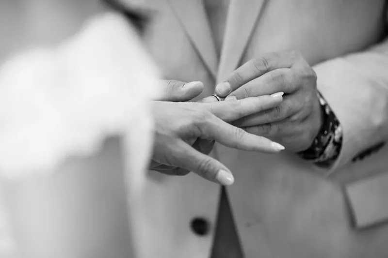 Gros plan en noir et blanc sur l'échange des alliances lors de la cérémonie civile à la mairie