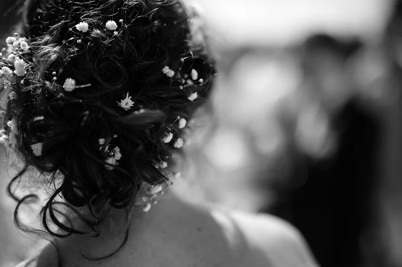 Détail artistique en contre-jour et flou poétique sur le chignon de la mariée