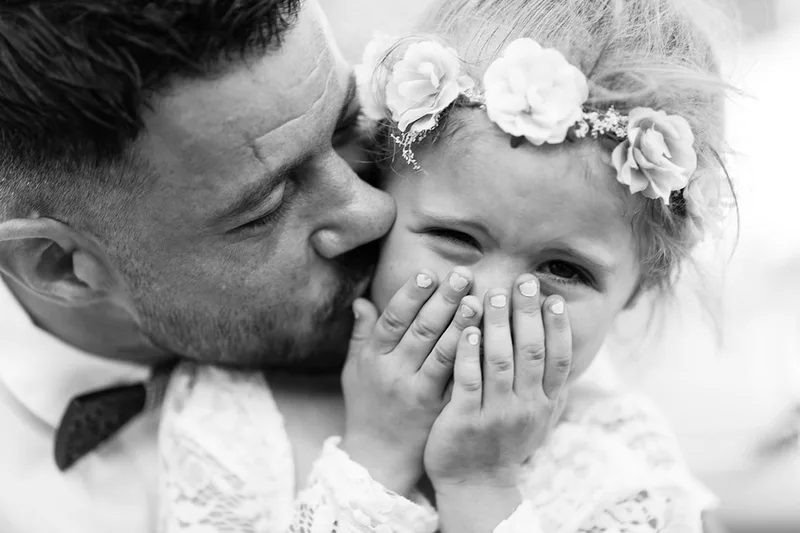 Photo sur le vif en noir et blanc d'un enfant en larmes tenant des fleurs durant la cérémonie
