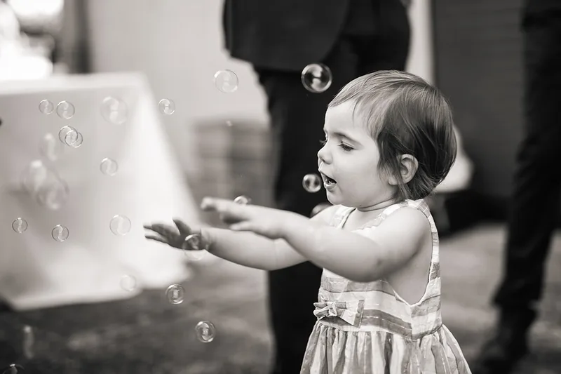 Image nostalgique au style vintage d'un enfant jouant avec des bulles de savon pendant la réception