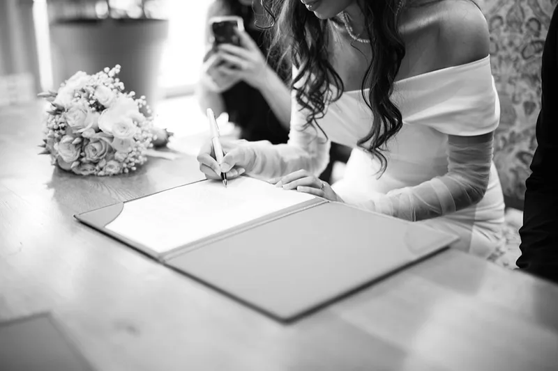 Portrait élégant et vintage en noir et blanc de la mariée signant les documents officiels